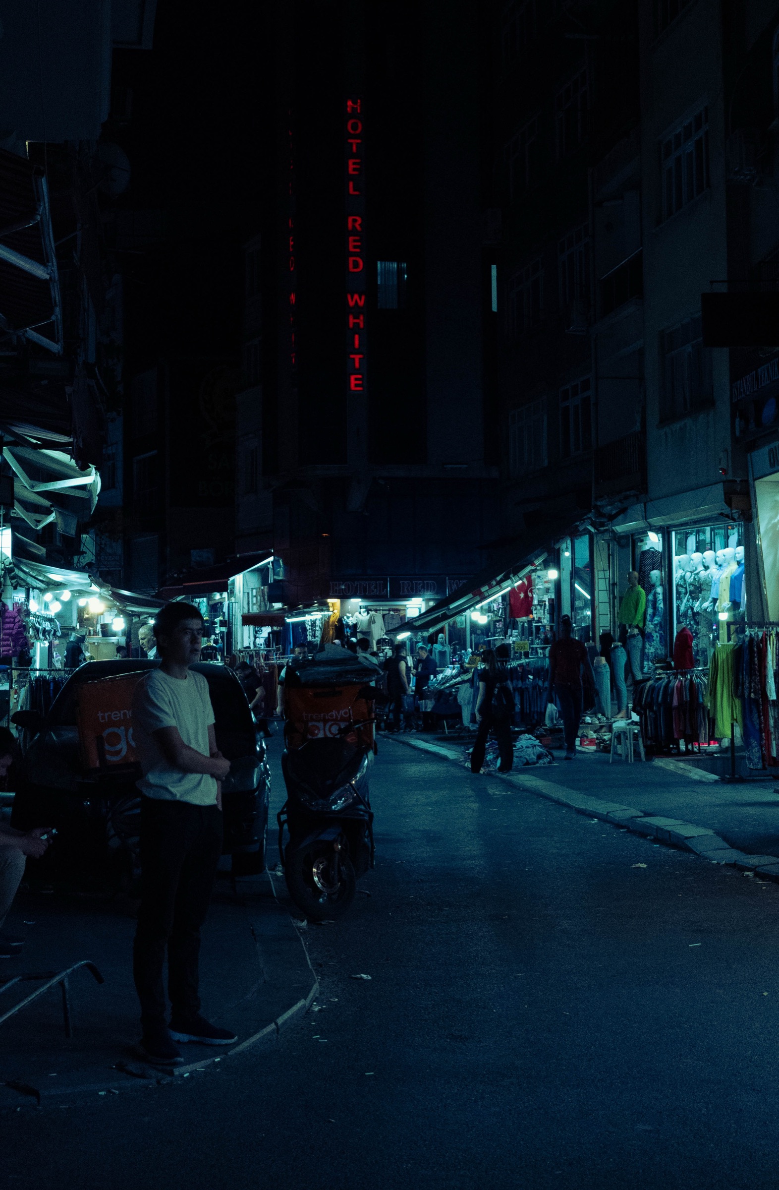 Rua de mercado noturno com letreiro de néon de hotel, Istambul