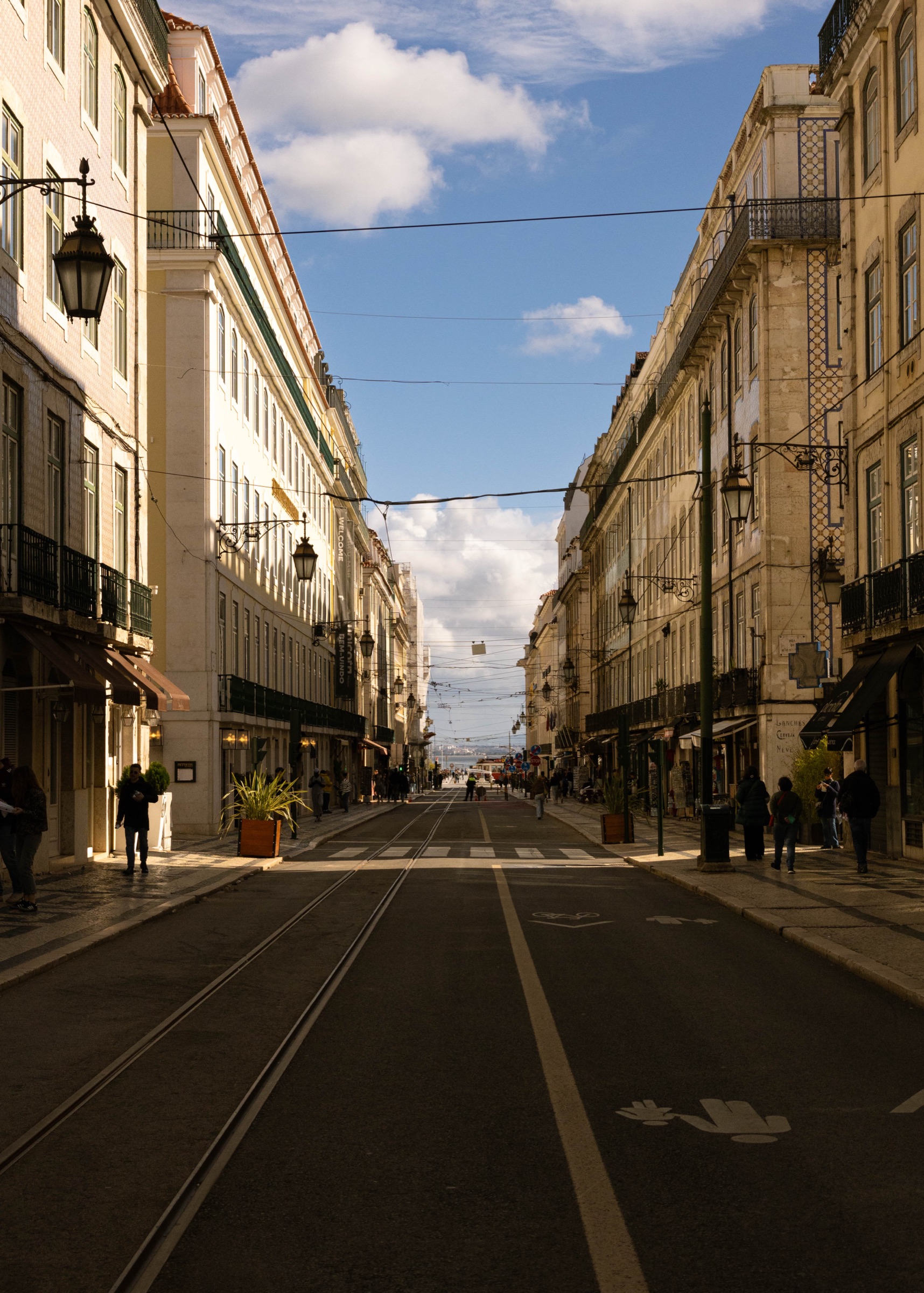 Carris do elétrico numa rua soalheira em direção ao Tejo, Lisboa
