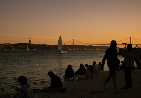 Silhuetas junto ao Tejo ao pôr do sol, com a Ponte 25 de Abril